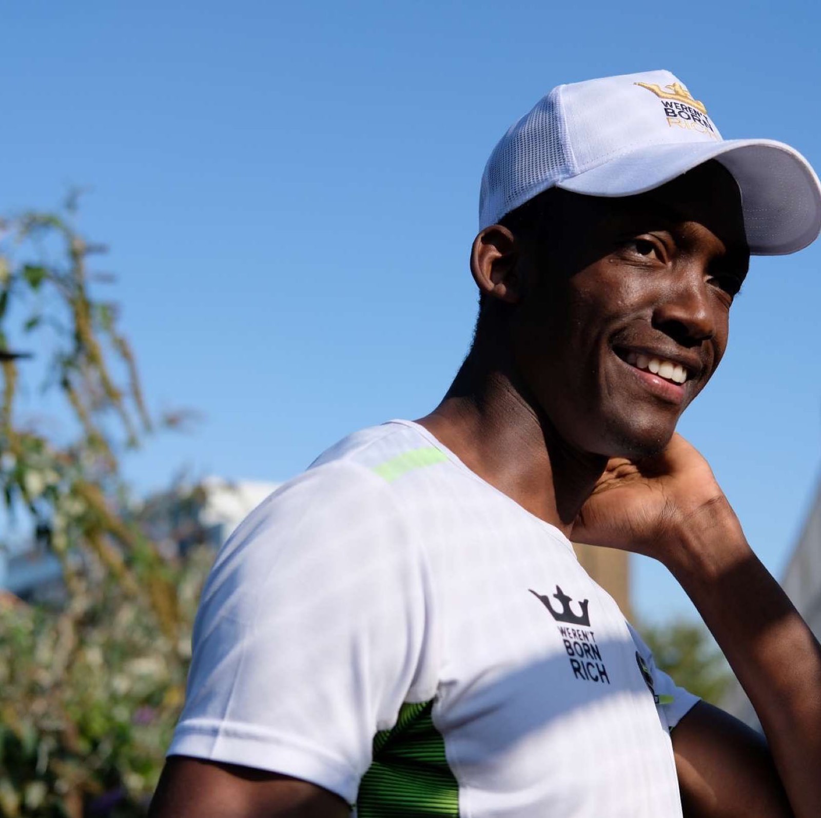 Hisham, personal trainer in London, smiling in a white training top and cap